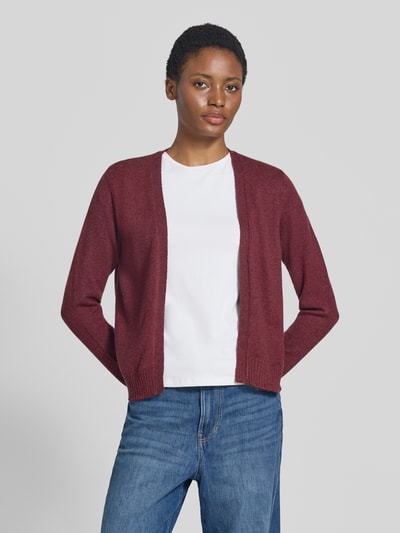 Frauenmodel trägt Strickjacke aus Viskose-Mix von VILA in Dunkelrot, gerade Passform, gerippte Bündchen, Jeans, Nahaufnahme Oberkörper.