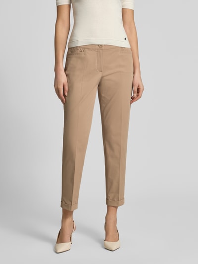 Frauenmodel trägt Chino aus Techno Cotton Superstretch Modell 'UTE' von Raffaello Rossi in Beige mit Bügelfalten und Beinumschlägen, Ganzkörperansicht von vorne. Elastischer-Material-Mix mit Baumwoll-Anteil, Straight Fit, Verkürzt, Knopf- und Reißverschluss, Eingrifftaschen, Gesäßtaschen, Gürtelschlaufen, Bundweite bei Größe 36: 40 cm, Innenbeinlänge bei Größe 36: 68 cm.