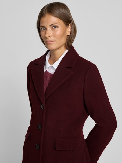 Vrouwenmodel draagt Mantel aus Woll-Mix met Reverskragen und Pattentaschen van FUCHS SCHMITT in bordeaux, straight fit, knoopsluiting, klepzakken, mix van wol en kasjmier, ruglengte maat 36: 95 cm, schouderbreedte maat 36: 42 cm, borstwijdte maat 36: 48 cm, mouwlengte maat 36: 66 cm, bovenlichaam close-up vooraanzicht.