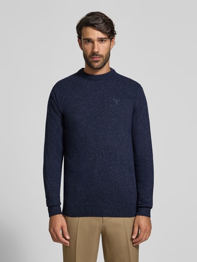 Männermodel trägt Pullover aus Woll-Seide-Mix mit Rundhalsausschnitt Modell 'TISBURY' von BARBOUR, dunkelblau meliert, Strickstruktur, Ganzkörperansicht von vorne.