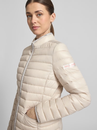 Frauenmodel trägt Steppjacke mit Reißverschlusstaschen Modell 'SISTER JUDY' von Frieda & Freddies in Beige, Nahaufnahme Oberkörper, Slim Fit, Stehkragen, dezente Steppstruktur, schlichtes Design