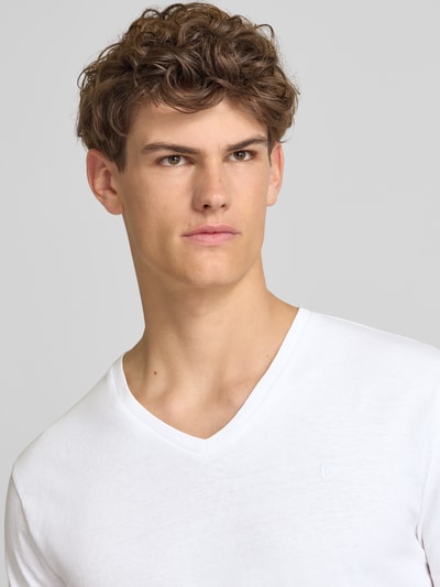Männermodel trägt T-Shirt aus Baumwoll-Leinen-Mix mit V-Ausschnitt von Superdry in Weiß, feine Struktur, Stitching, Regular-Fit, Nahaufnahme Oberkörper. Rückenlänge 68 cm bei Größe M.