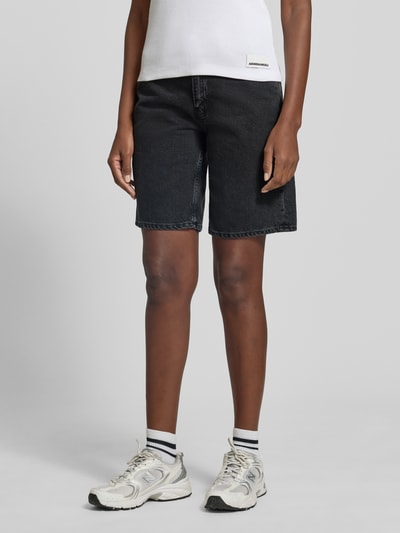 Vrouwenmodel draagt Regular Fit Jeansshorts uit puur katoen model 'THALINAA' van Armedangels in zwarte denim met label patch, vijf zakken, riemlussen, knoop- en ritssluiting, twillstructuur. Volledige vooraanzicht.