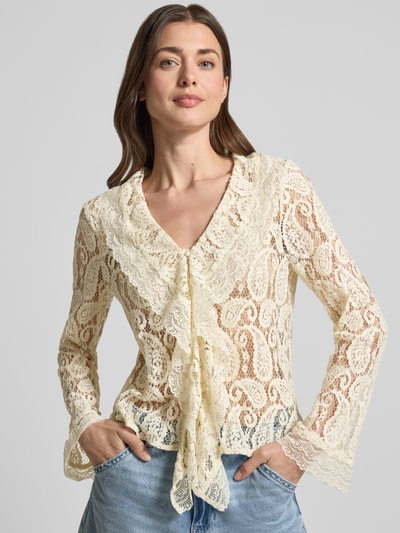 Kobiece modelka nosi Regular Fit Regular Fit aus Baumwoll-Mix Modell 'SALLY' od Vero Moda, półprzezroczysta damska bluzka z długim rękawem, abstrakcyjny wzór, koronkowa tekstura, kremowy kolor, głęboki dekolt V, falbaniasty kołnierz, zapinana na pojedynczy rząd guzików, widok na górną część ciała z przodu