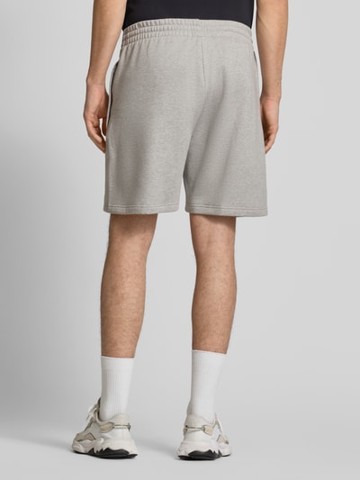 Männermodel trägt Regular Fit Sweatpants mit Logo-Stitching von adidas Originals in Hellgrau, knielang, Baumwoll-Mix, Rückansicht.