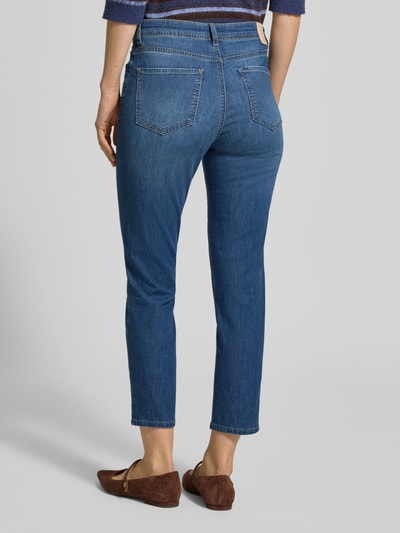 Modelka nosi Jeans in verkürzter Passform Modell 'Mary' von Brax, bawełniany mix ze streczem, zwężana nogawka, tylne kieszenie, niebieski denim, Szerokość w rozmiarze 36: 37 cm, długość wewnętrzna nogawki 69 cm, widok całej sylwetki z tyłu.