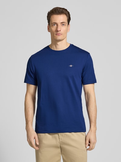 Männermodel trägt Regular Fit T-Shirt mit Logo-Stitching von Gant in Blau, reine Baumwolle, Rundhalsausschnitt, Ganzkörperansicht von vorne.