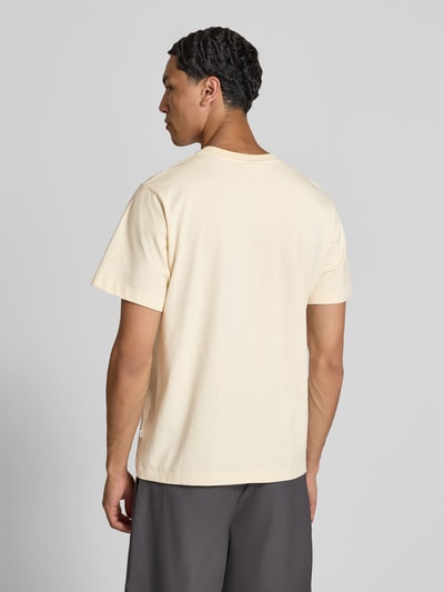 Männermodel trägt Regular Fit T-Shirt mit Motiv-Print von Forét in heller Farbe aus reiner Baumwolle, Rückenlänge 67 cm, Ganzkörperansicht Rückansicht.