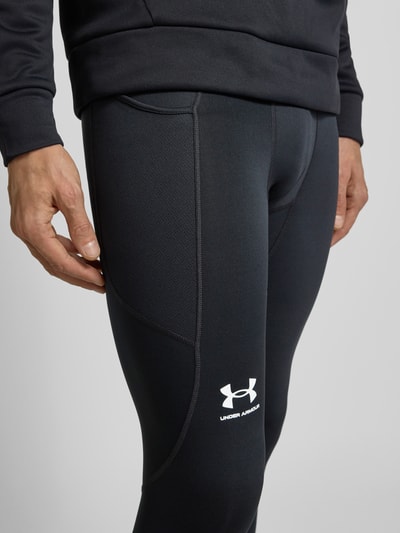 Męski model nosi Leggings mit elastischem Bund und Logo od Under Armour, czarny kolor, dopasowany krój, widoczne logo, zbliżenie na uda.