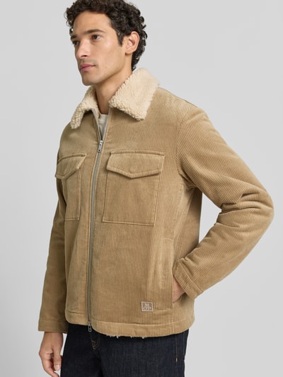 Männermodel trägt Regular Fit Cordjacke aus reiner Baumwolle von Marc O'Polo in Beige mit Stehkragen und sichtbarer Struktur, Ganzkörperansicht von vorne. Kontext: Herren Daunenjacke von Marc O'Polo.
