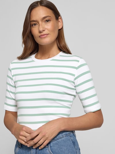 Frauenmodel trägt Basic T-Shirt Ringel O-Neck von Christian Berg Woman, Baumwoll-Elasthan-Mix, körpernah, halbarm, grün-weiß gestreift, Nahaufnahme Oberkörper.