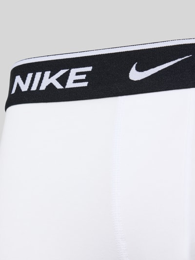 Männermodel trägt weiße Trunks aus Baumwoll-Mix Modell 'ESSENTIAL' von Nike mit elastischem Logo-Bund, Nahaufnahme Oberkörper.