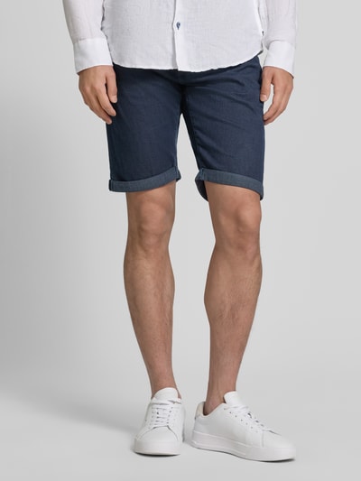Männermodel trägt Jeansshorts mit Label-Detail von Pierre Cardin in Dunkelblau, Baumwoll-Mix mit Stretch-Anteil, Eingrifftaschen, Umschlag, Regular-Fit, Ganzkörperansicht von vorne.