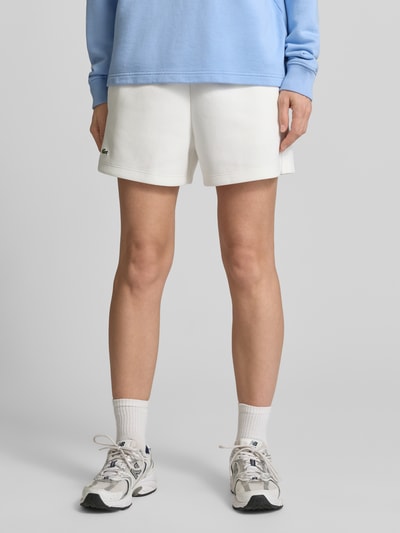 Kobiece model nosi Regular Fit Sweatshorts aus reiner Baumwolle von Lacoste, efekt: jednolity kolor, krój regular fit, wyhaftowane logo, tunel, ściągacz, bawełna, zdjęcie: z przodu, zbliżenie na dolną część ciała.