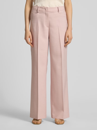 Modelka nosi Hose aus Viskose-Mix mit Bügelfalten von More & More, jasnoróżowy kolor, szeroka nogawka, kieszenie, szerokość w rozmiarze 36: 39 cm, długość nogawki od wewnątrz w rozmiarze 36: 80 cm, widok całej sylwetki z przodu.