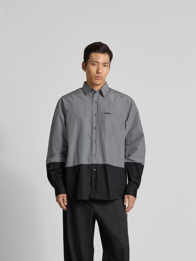Männermodel trägt Relaxed Fit Freizeithemd mit Brusttasche von VETEMENTS aus Baumwoll-Mix, kariertes Muster, Langärmlig, Ganzkörperansicht von vorne.