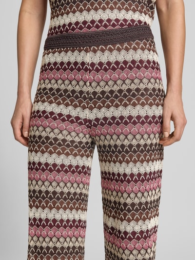 Frauenmodel trägt Hose im Allover-Look mit elastischem Bund von MORE & MORE, Strukturmuster in Braun, Rosa, Beige, Nahaufnahme Oberkörper.