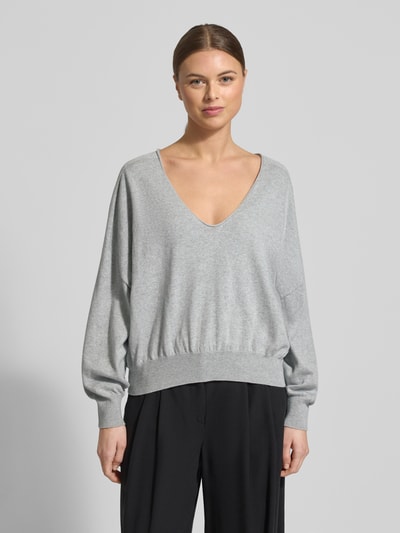 Frauenmodel trägt Strickpullover aus Baumwoll-Kaschmir-Mix Modell 'RISORY' von Drykorn in Hellgrau, Relaxed-Fit, V-Ausschnitt, Ganzkörperansicht von vorne. Rückenlänge bei Größe S: 53 cm, Ärmellänge: 48 cm.