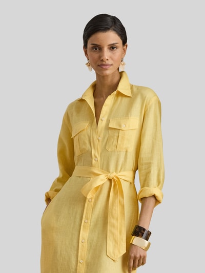 Frauenmodel trägt Schmales Midi Hemdblusenkleid aus reinem Leinen von Lauren Ralph Lauren, Optik: Unifarben, Passform: Schmal, Midi-Länge, V-Ausschnitt, Label-Prägung, Gürtelschlaufen, abnehmbarer Gürtel, Knopfleiste, Ärmelform: Langarm, Ärmelabschluss: Manschette, gerader Saum, aufgesetzte Seitentaschen, Materialverarbeitung: Flammgarn, Material: Leinen, warmes Gelb, leicht strukturierte Oberfläche, Nahaufnahme Oberkörper.