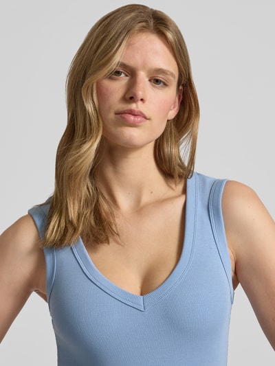Modelka kobieca ma na sobie Slim Fit Top mit V-Ausschnitt von Gina Tricot, jasnoniebieski, bawełniany materiał prążkowany, krój slim fit, dekolt V, bez rękawów, długość tyłu S 52 cm, zbliżenie na górną część ciała.