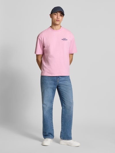 Männermodel trägt Regular Fit T-Shirt aus reiner Baumwolle Modell 'IN A RUSH' von PROHIBITED in Rosa, Jeans und Sneakers, Ganzkörperansicht von vorne.