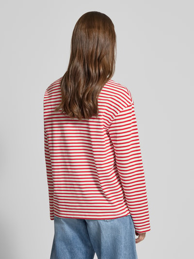 Młodzieżowy model prezentuje Regular Fit Langarmshirt aus Baumwoll-Mix Modell 'SADIE' od Pieces, pasiasty wzór, krój regular fit, różowe i czerwone pasy, długi rękaw, okrągły dekolt, materiał bawełniany, widok całej sylwetki z tyłu.