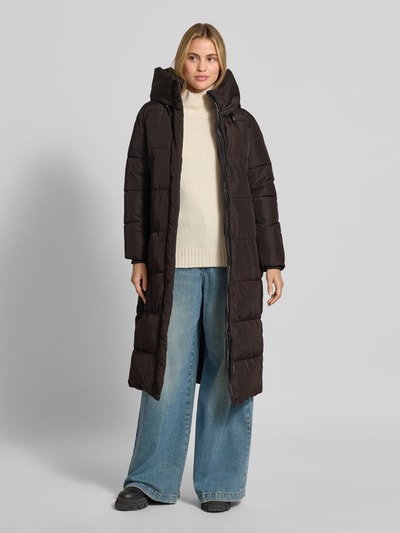 Frauenmodel trägt Regular Fit Mantel in Stepp-Optik Modell 'SOULANI' von khujo, Farbe Dunkelbraun, glatte Textur, Ganzkörperansicht von vorne. Damen Mantel mit Kapuze, Stehkragen und Eingrifftaschen, Rückenlänge 117 cm, Schulterbreite 43 cm, Brustweite 50 cm, Ärmellänge 62 cm.