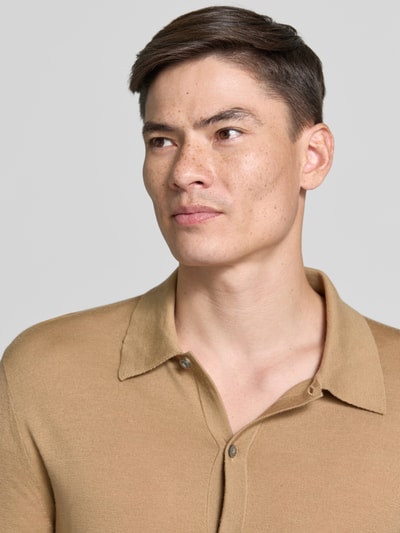 Męski model nosi Regular Fit Strickjacke aus Wolle Modell 'Verklin' von Tiger Of Sweden, kołnierzyk typu kent, listwa guzikowa, beżowa, krój regular fit, czysta wełna, długość tyłu 71 cm, długość rękawów 65 cm, zbliżenie na górną część ciała.