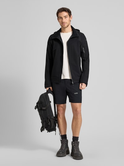 Męski model nosi Regular Fit kurtka z kapturem model 'BARMSTEDT' od Icepeak, kolor czarny, kieszenie, zamek błyskawiczny, nadruk z logo, wpuszczane kieszenie, kieszeń na rękawie, stójka, długość tyłu w rozmiarze 50: 78 cm, szerokość ramion w rozmiarze 50: 43 cm, szerokość klatki piersiowej w rozmiarze 50: 54 cm, długość rękawów w rozmiarze 50: 71 cm, gładka faktura, całkowity widok z przodu