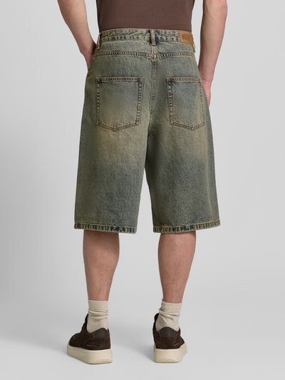 Männermodel trägt Jeansshorts mit Eingrifftaschen Modell 'Yuto Aged' von WOODBIRD in Relaxed-Fit aus Reine Baumwolle, Ganzkörperansicht Rückansicht. Bundweite 44 cm, Innenbeinlänge 33 cm, Größe 32.