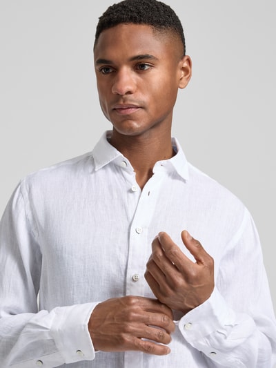 Männermodel trägt Slim Fit Leinenhemd mit Haifischkragen von Fynch-Hatton, reines Leinen, weiß, Label-Stitching, Nahaufnahme Oberkörper.