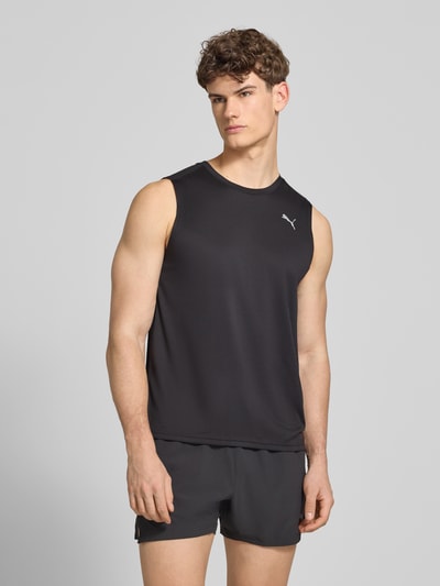 Männermodel trägt Top mit Logo und Rundhalsausschnitt von PUMA PERFORMANCE in Schwarz, Regular Fit, glatte Textur, Ganzkörperansicht von vorne.