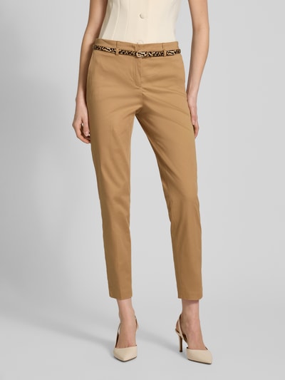 Kobiece modelka nosi Slim Fit Hose in verkürzter Passform mit Gürtel od Christian Berg Woman, kolor beżowy, bawełna z domieszką wiskozy, krój slim fit, pasek, szerokość w rozmiarze 36: 39 cm, długość wewnętrzna nogawki w rozmiarze 36: 72 cm, zdjęcie całej sylwetki z przodu.