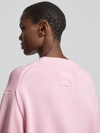 Frauenmodel trägt Oversized Wollpullover aus Woll-Mix von Nanushka in Rosa mit Strick-Optik, Stehkragen und gerippten Abschlüssen, Nahaufnahme Oberkörper, Rückenansicht.