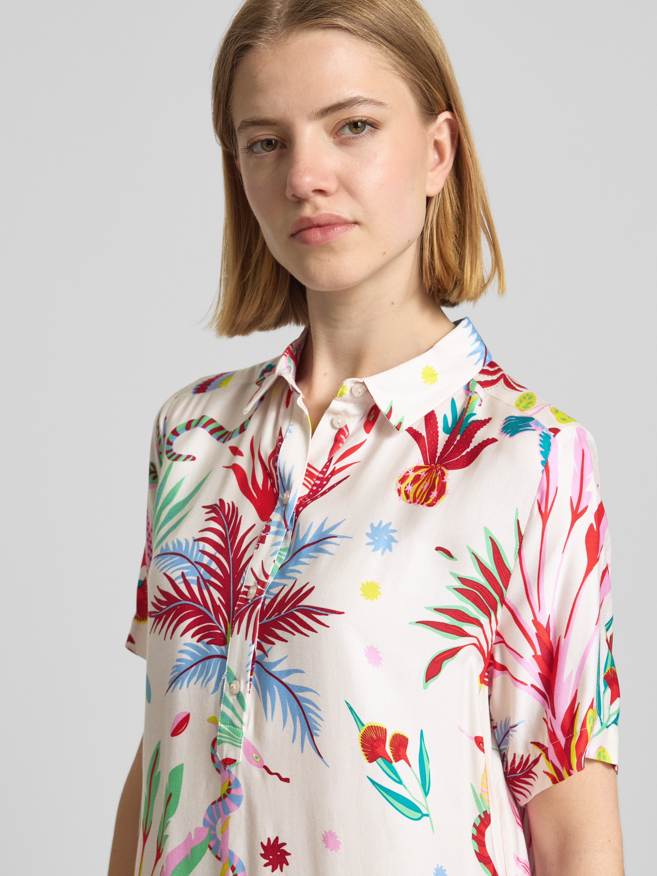 Frauenmodel trägt Knielanges Hemdblusenkleid aus Viskose mit Knopfleiste von Milano Italy, bunt gemustert, lockerer Schnitt, Nahaufnahme Oberkörper.