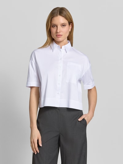 Frauenmodel trägt Hemdbluse mit Brusttasche und Kentkragen von More & More aus weißem Baumwoll-Mix mit Stretch-Anteil, Regular-Fit, Knopfleiste, leicht überschnittene Schultern, Rückenlänge 53 cm, Ärmellänge 30 cm, Ganzkörperansicht von vorne.