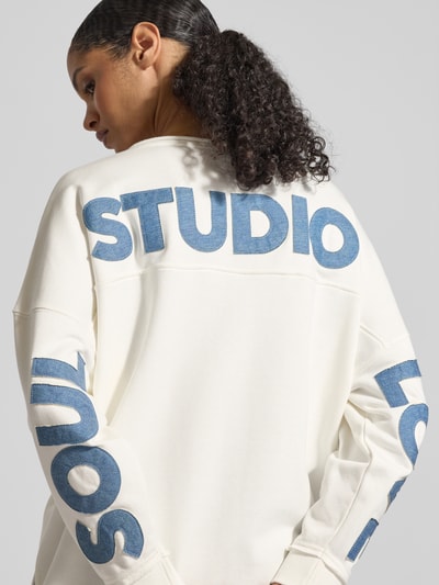 Frauenmodel trägt Oversized Sweatshirt aus Baumwoll-Mix von Smith & Soul in Weiß mit blauen Schriftzügen, elastische Ärmelabschlüsse, Ganzkörperansicht Rückansicht.