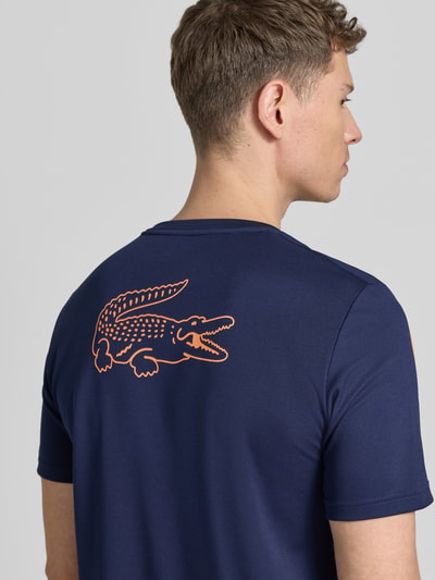Männermodel trägt Regular Fit T-Shirt mit UV-Schutz 50+ von Lacoste Sport in Dunkelblau, Logo-Print, Piqué-Textur, Ganzkörperansicht Rückansicht