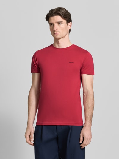 Männermodel trägt T-Shirt mit Label-Detail van Gant in rood, puur katoen, recht model, ronde hals, ruglengte maat M 70 cm, Ganzkörperansicht van voren.