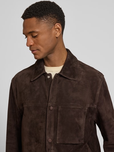 Männermodel trägt Regular Fit Lederjacke aus echtem Ziegenleder Modell 'C-MOLOT' van BOSS in donkerbruin nubuck met opgestikte borstzak en omlegkraag, label-applicatie, drukknoopsluiting en zijzakken, Nahaufnahme Oberkörper.