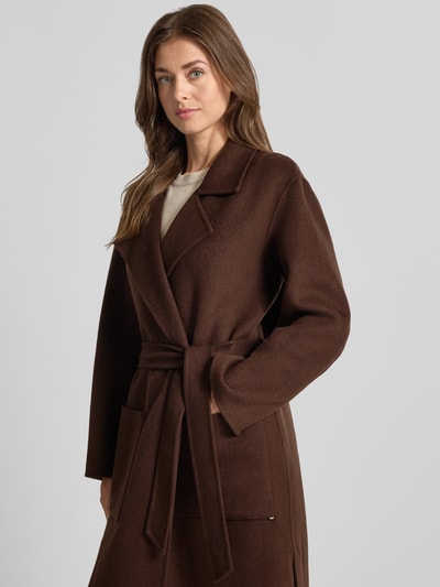 Modelka nosi płaszcz z mieszanki wełny model 'ALLEGORIA' marki OAKWOOD, ozdobne obszycie, tasiemka w talii, miękka brązowa faktura, widok z przodu, zbliżenie górnej części.