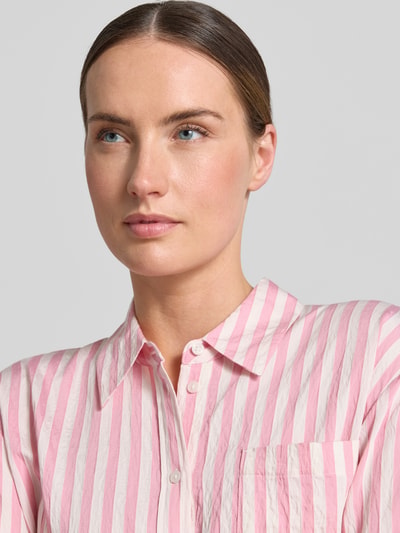 Frauenmodel trägt Relaxed Fit Bluse aus Viskose-Mix von Comma mit rosa-weißen Streifen, Hemdblusenkragen, Knopfleiste, Nahaufnahme Oberkörper. Rückenlänge bei Größe 36: 76 cm, Ärmellänge: 57 cm.