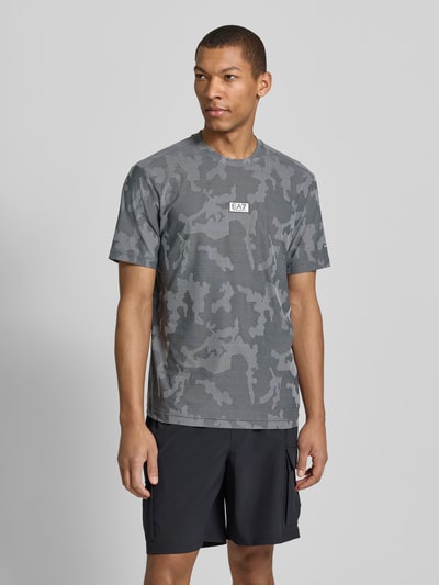 Mannelijk model draagt T-Shirt met Rundhalsausschnitt und Label-Detail van EA7 Emporio Armani in regular fit, grijs camouflagepatroon, materiaal-mix met stretch, ruglengte maat M 69 cm, voorkant volledige lichaamsweergave.