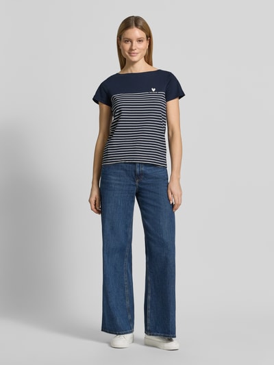 Frauenmodel trägt Regular Fit T-Shirt aus reiner Bio-Baumwolle von Tom Tailor, gestreift, navy-weiß, Herz-Print, Ganzkörperansicht von vorne.