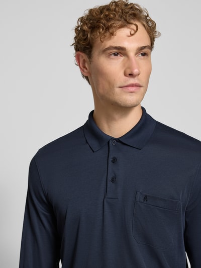 Männermodel trägt Regular Fit Poloshirt aus Baumwoll-Mix von RAGMAN in Dunkelblau, sichtbare Brusttasche, Nahaufnahme Oberkörper. Herren Poloshirt, elastische Abschlüsse, langärmeliges Design, Rückenlänge bei Größe M 70 cm.