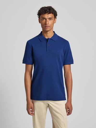 Männermodel trägt Regular Fit Poloshirt aus reiner Baumwolle Modell 'PALLAS' von BOSS in Unifarbe Blau, Piqué-Struktur, Ganzkörperansicht von vorne.