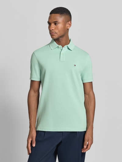 Męski model nosi Regular Fit Poloshirt aus Baumwoll-Mix od Tommy Hilfiger, mięta, bawełniany piké, krótki rękaw, logo, przód, ujęcie całej sylwetki z przodu.