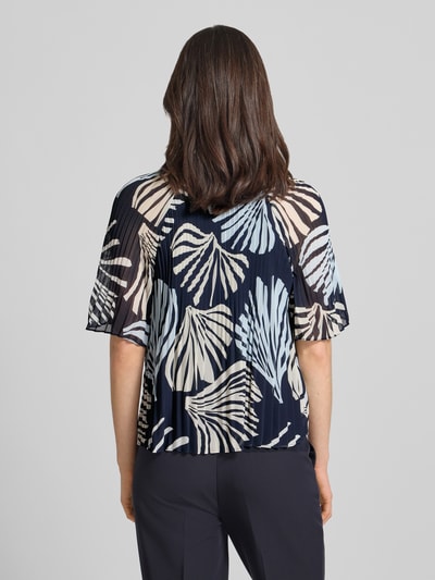 Frauenmodel trägt Regular Fit Blusenshirt in Plissee-Optik von s.Oliver BLACK LABEL, efekt: wzór na całej powierzchni, krój regular fit, kształt kołnierza: kołnierz z falbanami, detale: plisy, dekolt: okrągły dekolt, wycięcie w kształcie łezki, zapięcie: wiązanie, rękaw: krótki rękaw; widok całej sylwetki z tyłu
