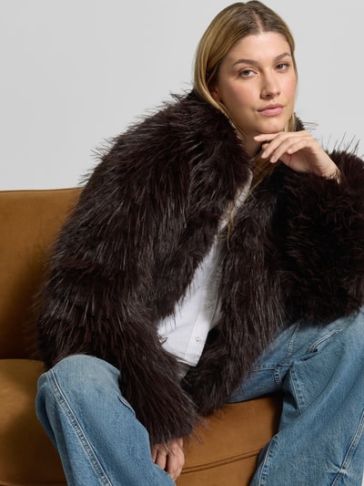 Vrouwenmodel draagt Jacke aus Kunstfell mit Stehkragen van Rich & Royal in donkerbruin imitatiebont, regular fit, opstaande kraag, zichtbare textuur en witte blouse, Ruglengte bij maat 36: 54 cm, Schouderbreedte bij maat 36: 45 cm, Borstwijdte bij maat 36: 47 cm, Mouwlengte bij maat 36: 63 cm, Nahaufnahme Oberkörper.