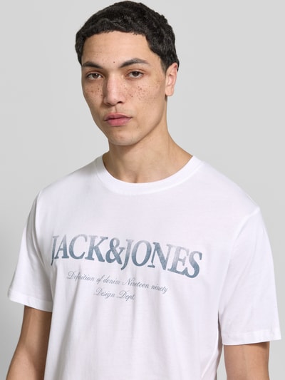 Männermodel trägt weißes T-Shirt aus Baumwolle Modell 'DEVIN' von Jack & Jones mit Label-Print, Nahaufnahme Oberkörper.
